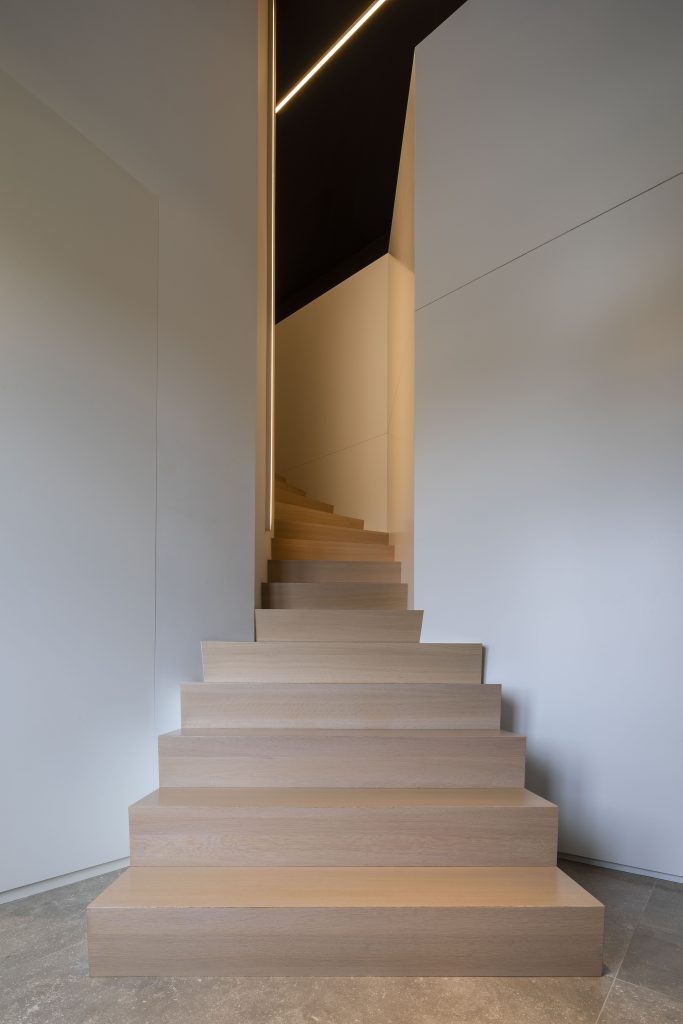 Escalier en béton recouvert de marches et contre-marches en chêne 3 plis. e garde-corps à l'étage est en MDF laqué et satiné blanc