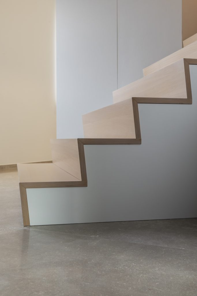 Escalier en béton recouvert de marches et contre-marches en chêne 3 plis. e garde-corps à l'étage est en MDF laqué et satiné blanc