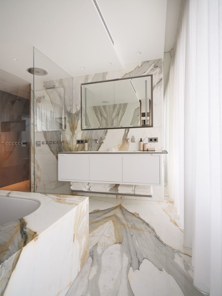 Salle de bain parentale avec meuble lavabo sur mesure réalisé en Corian. Le miroir possède deux bandes LED intégrées