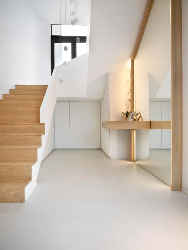 hall d'entrée contemporain, en blanc et chêne clair avec un grand miroir et des placards sur mesure, sous l'escalier