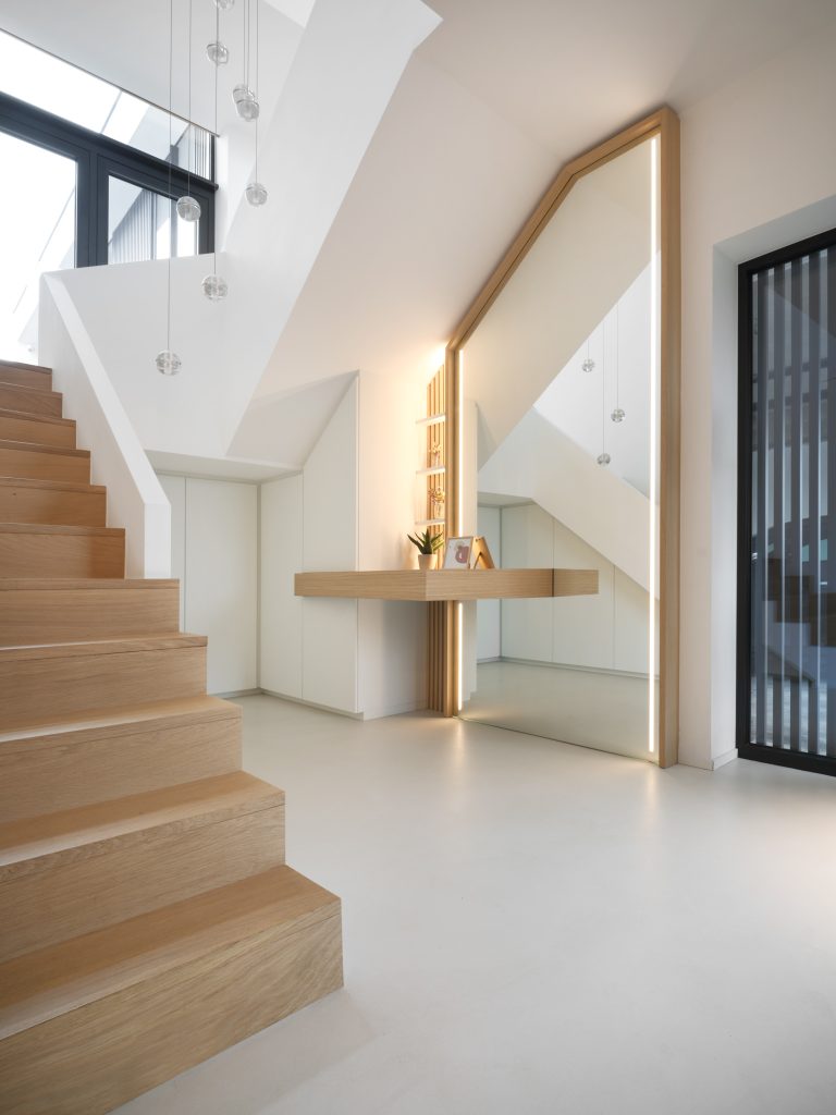 hall d'entrée contemporain, en blanc et chêne clair avec un grand miroir et des placards sur mesure, sous l'escalier